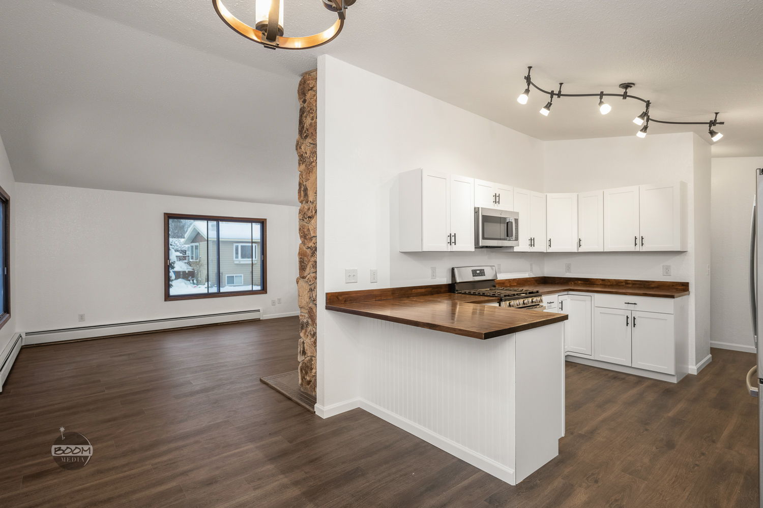 Renovated kitchen with white cabinets and butcher-block counters opening to the living room
