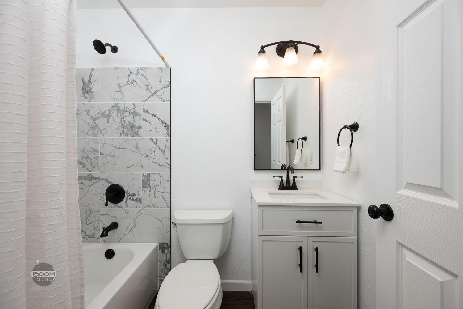 Bathroom with a marble-look tub surround and a white vanity