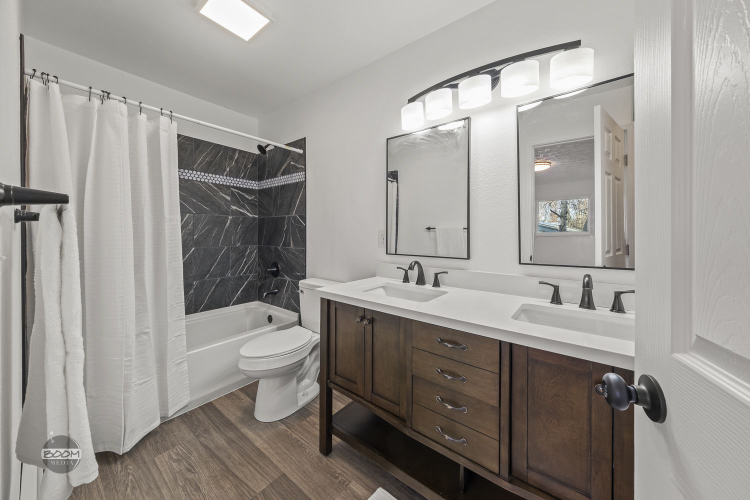 Double-vanity bathroom with a skylight and tiled tub surround