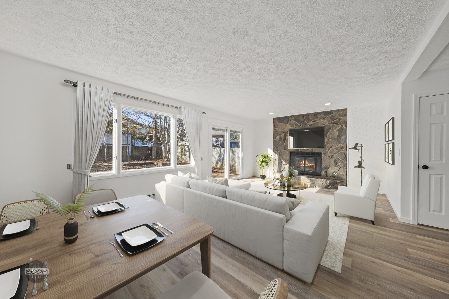 Renovated open living room with a stone fireplace and new wide-plank flooring